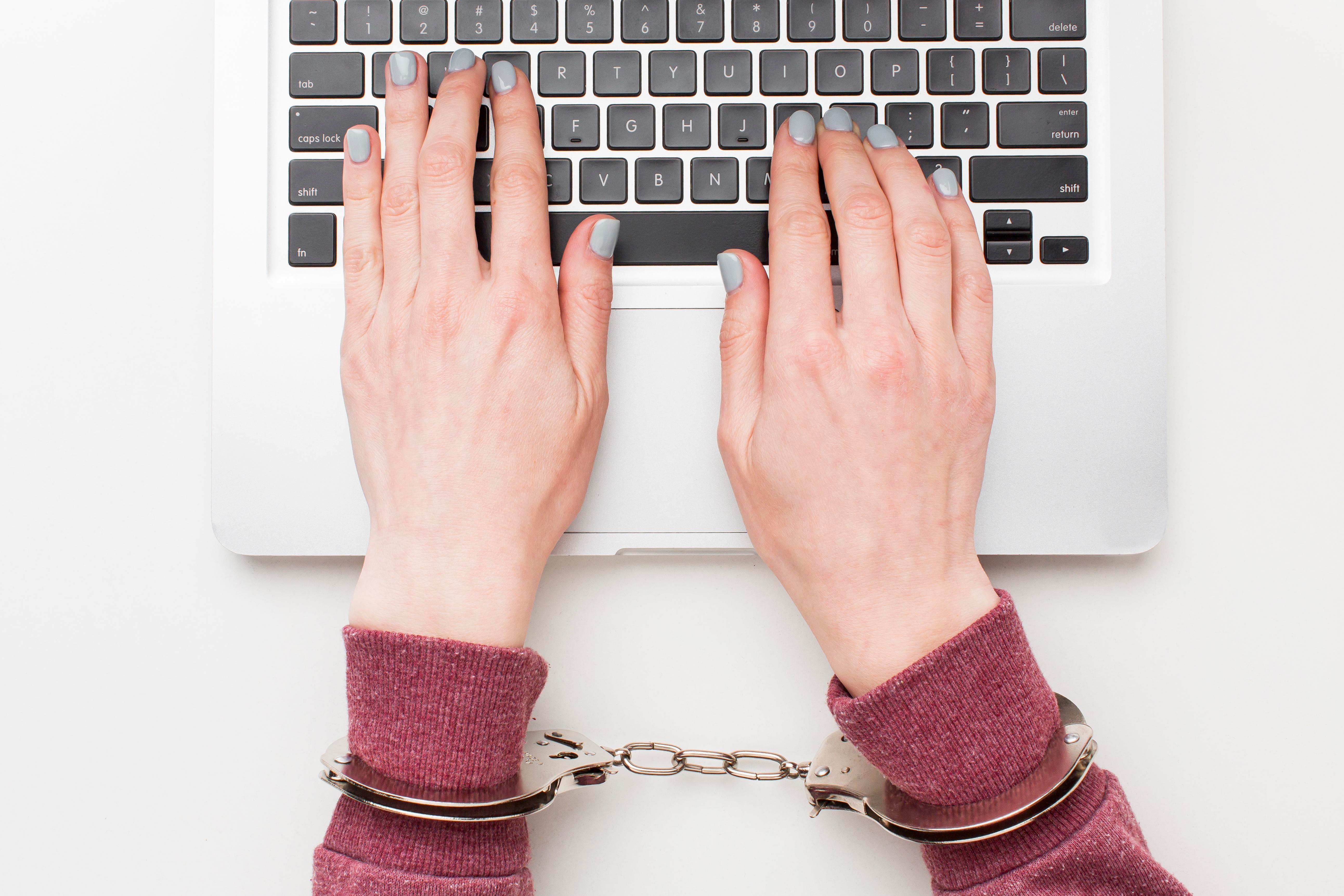 top-view-hands-with-handcuffs-working-laptop (1).jpg